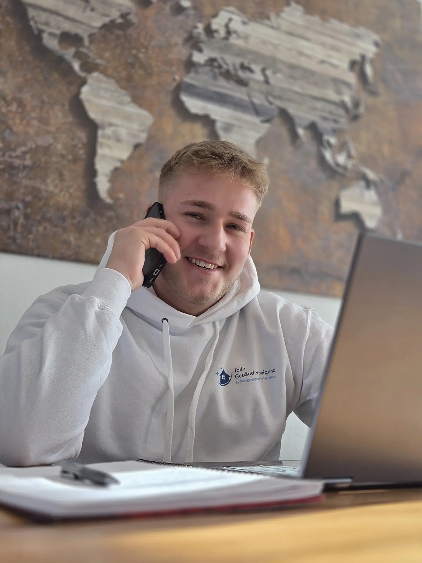 Nick Tolle telefoniert und lächelt dabei in die Kamera.
